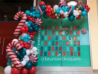 Holiday balloon demi arch at mall celebrating kindness with candy canes