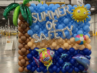 Amazon safety team balloon wall in warehouse Summer of Safety beach theme palm tree